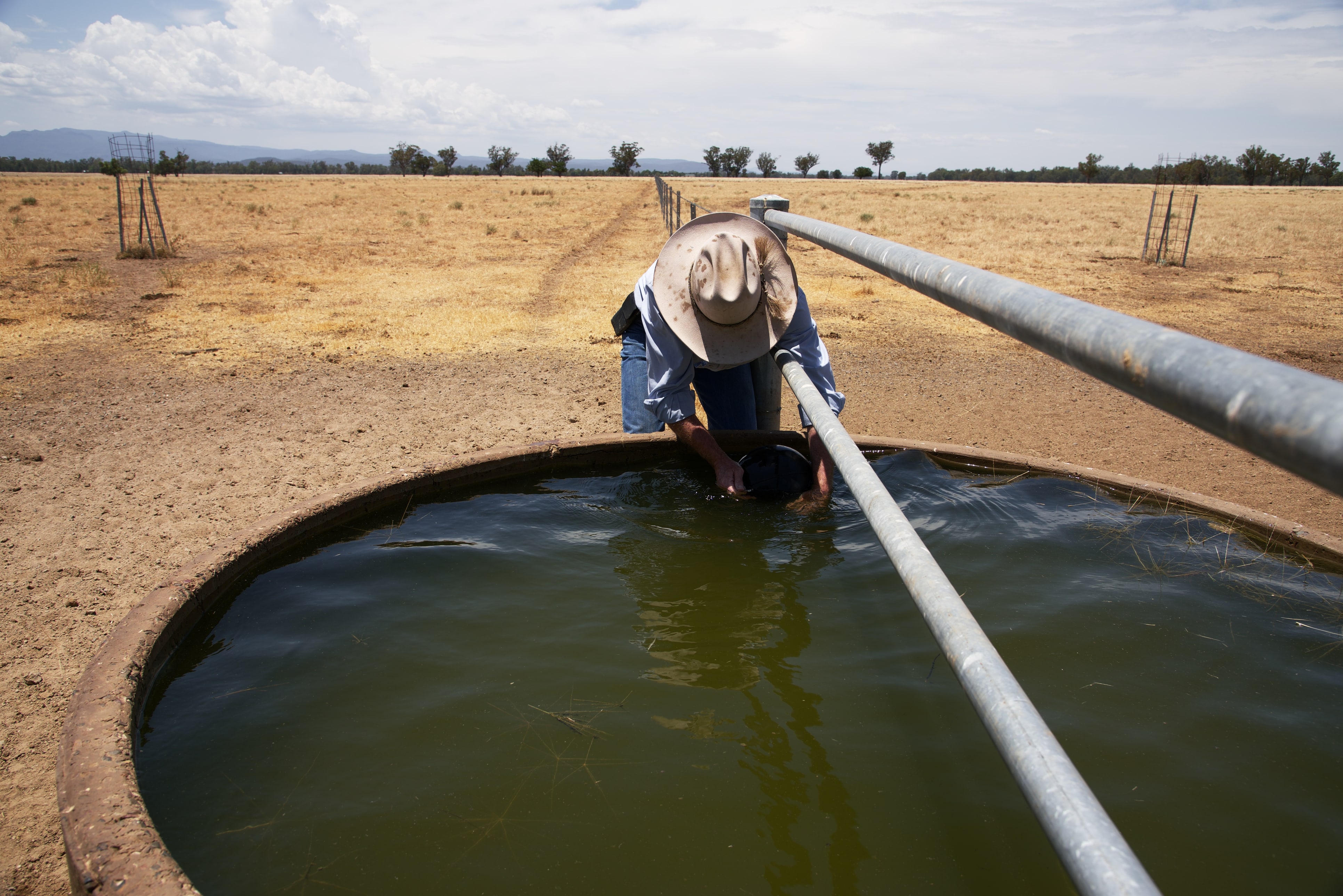 Farmer leaning over a water tank