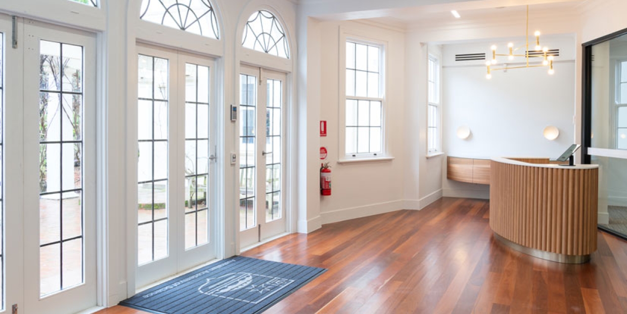 Inside of the building, showing large windowed doors and wooden flooring