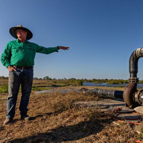 Farmer standing next to a water irrigation pipeline
