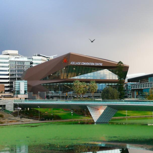 A landscape photo with the Adelaide Convention Centre behind a bridge over a river